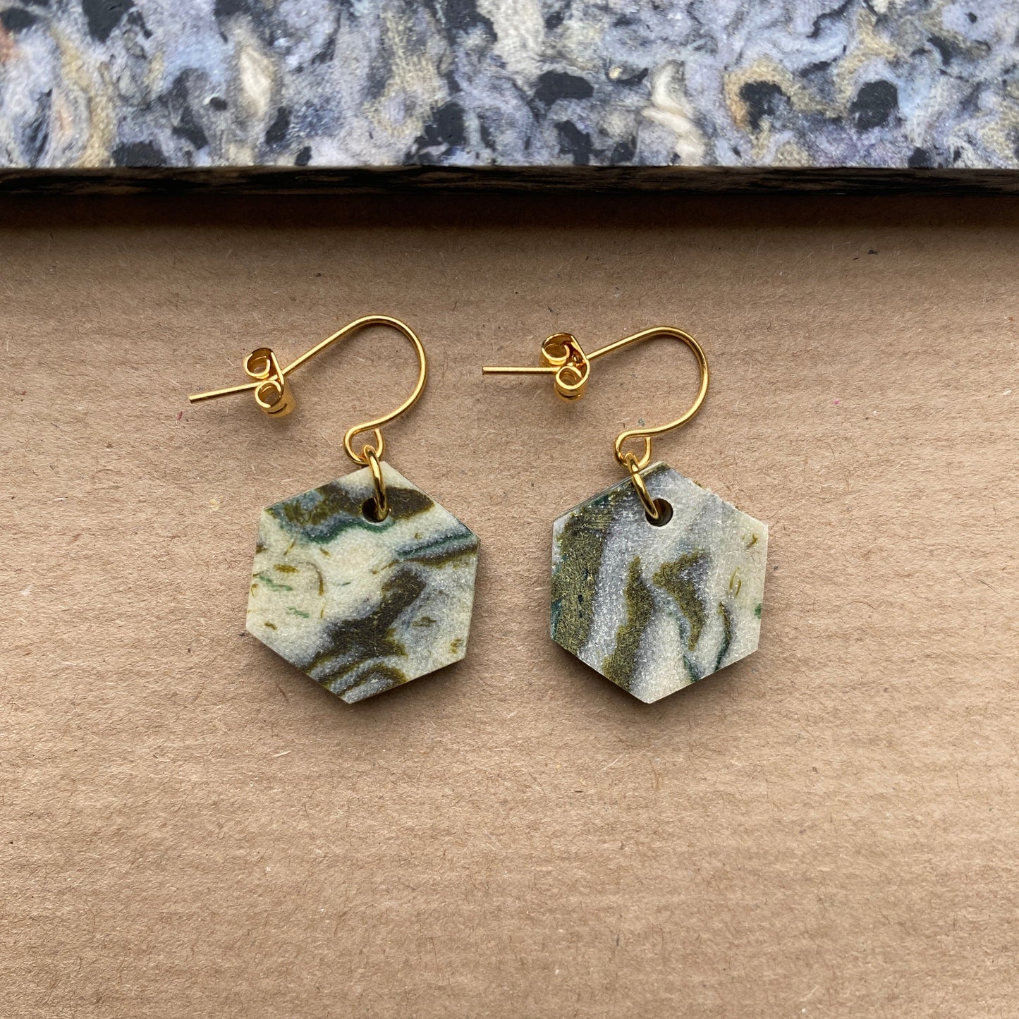 Eco-friendly hexagon earrings crafted from upcycled Fabreco textile waste in ivory, sage green, and charcoal hues with gold-plated hooks, sustainable fashion accessory.