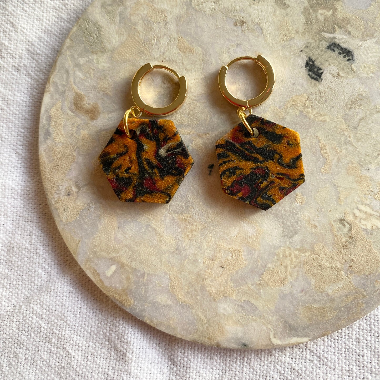 Pair of earrings with tiger stripe pattern on a stone surface