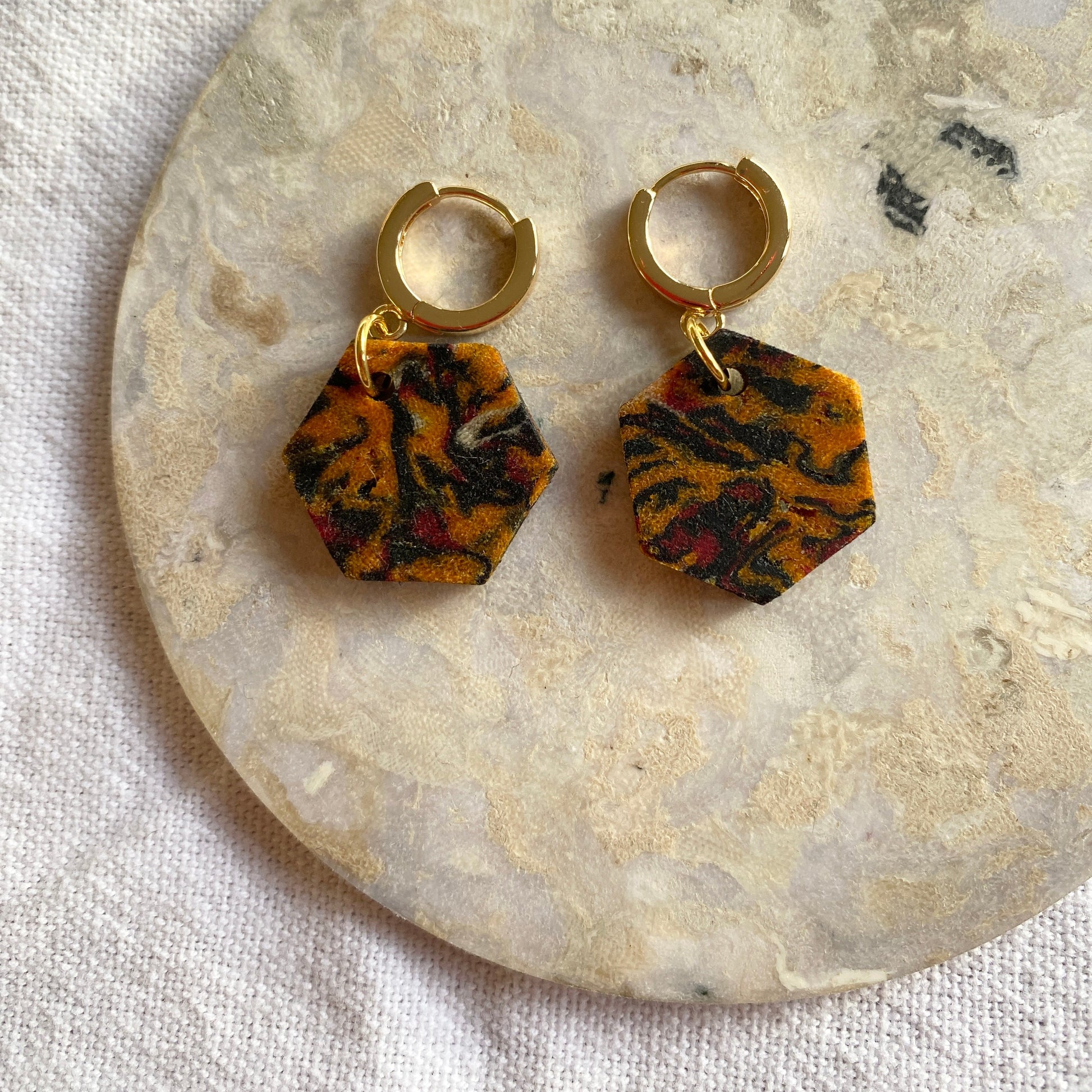 Pair of earrings with tiger stripe pattern on a stone surface