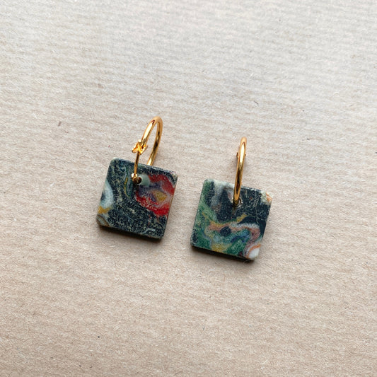 Square-shaped sustainable hoop earrings made from upcycled Fabreco with a marbled black, green, and red pattern, finished with gold-plated hoops.